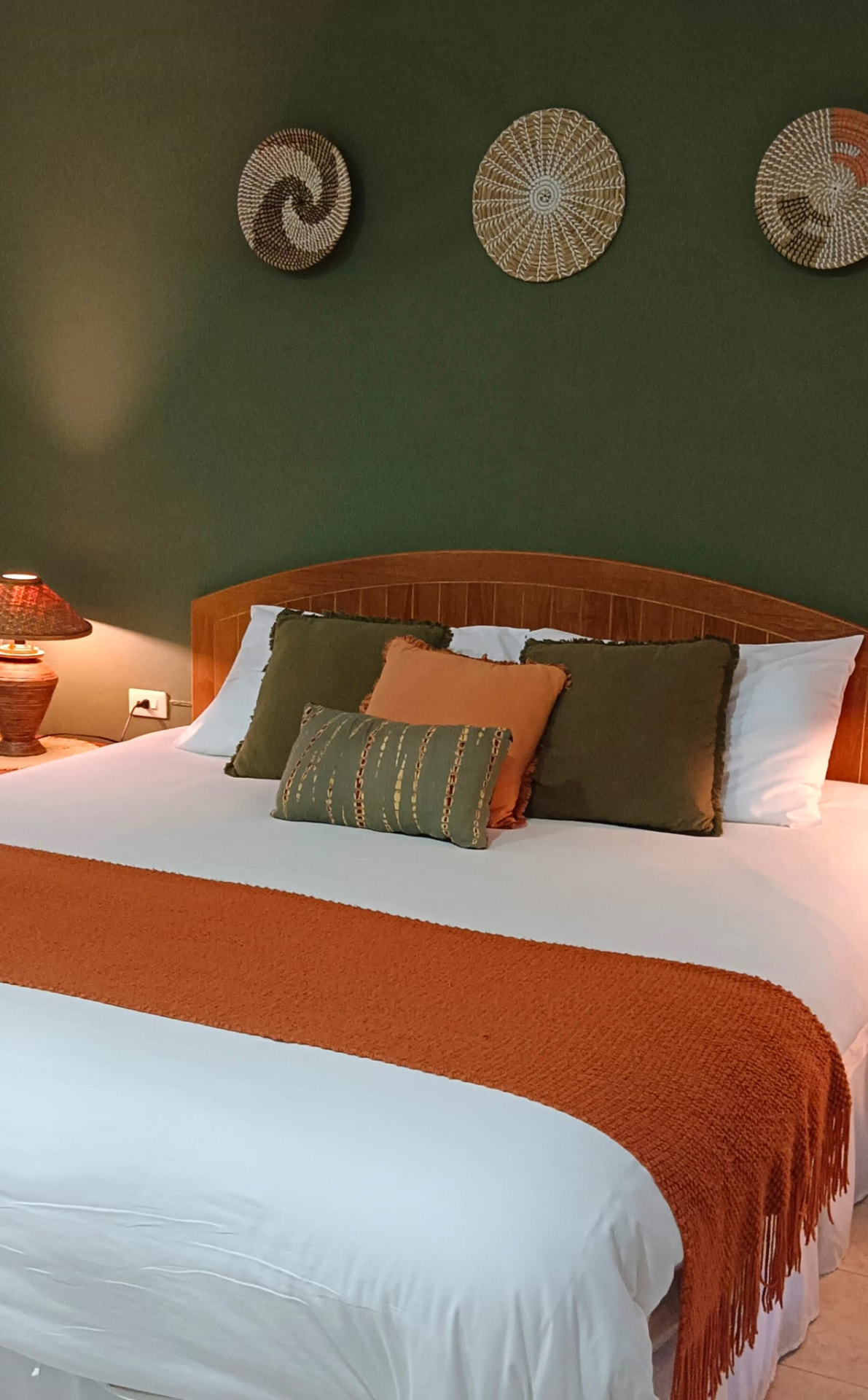 Comfortable king bed with green feature wall