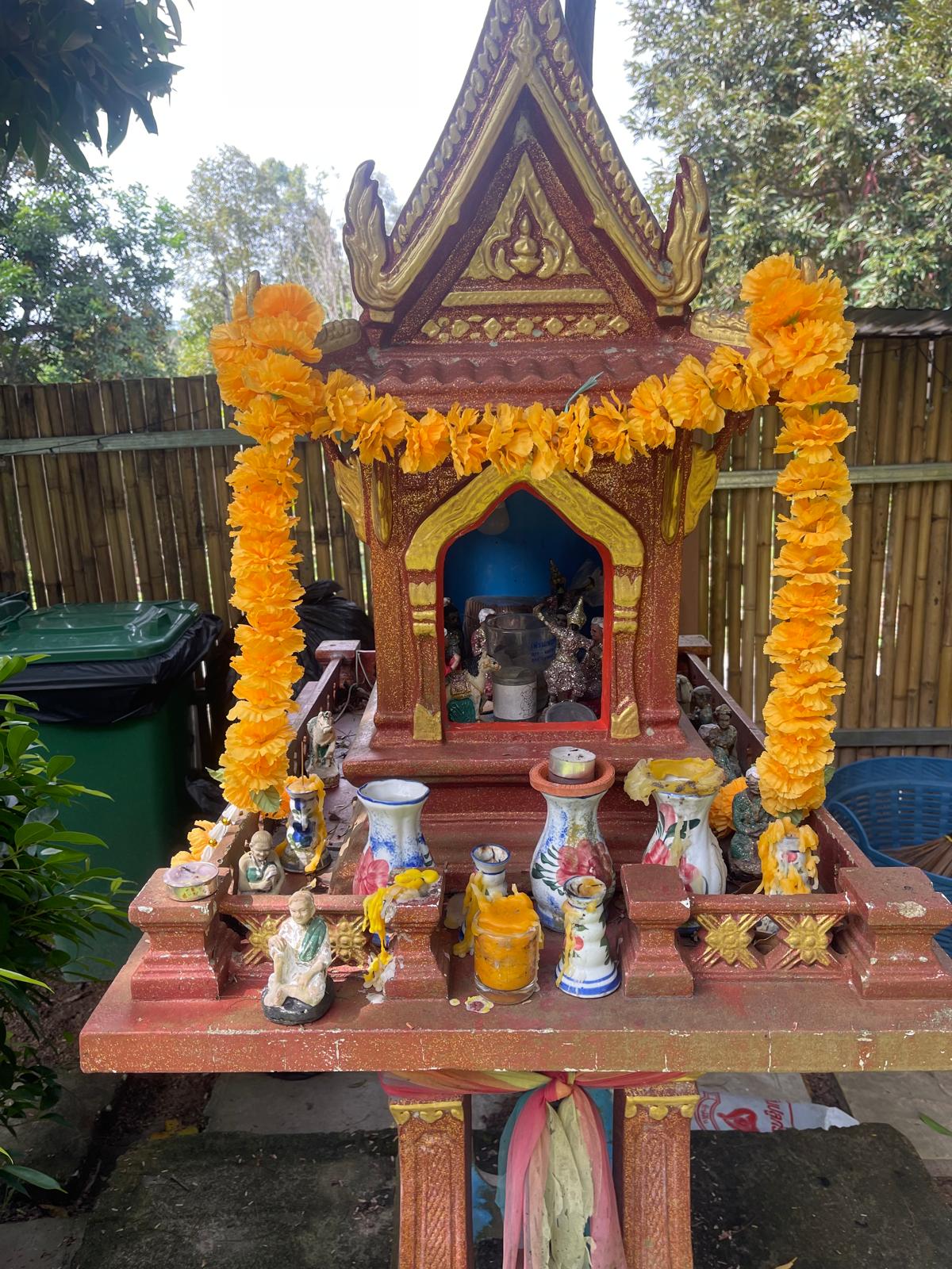 Thai spirit house decorated with marigold garlands